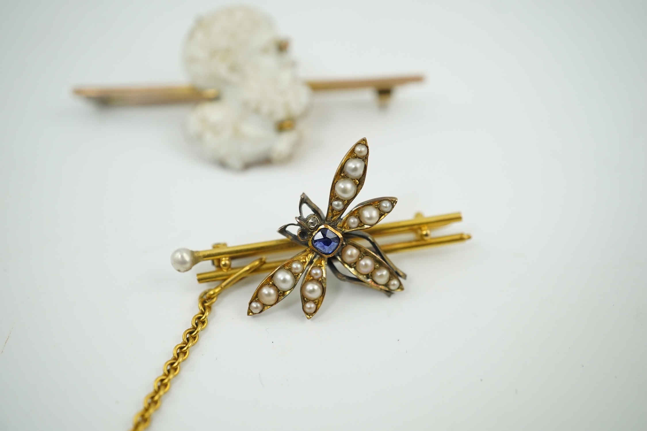 An Edwardian 15ct mounted cameo shell bar brooch, 49mm, together with a yellow metal, sapphire and split pearl cluster set dragonfly bar brooch, 11 grams. Condition - fair